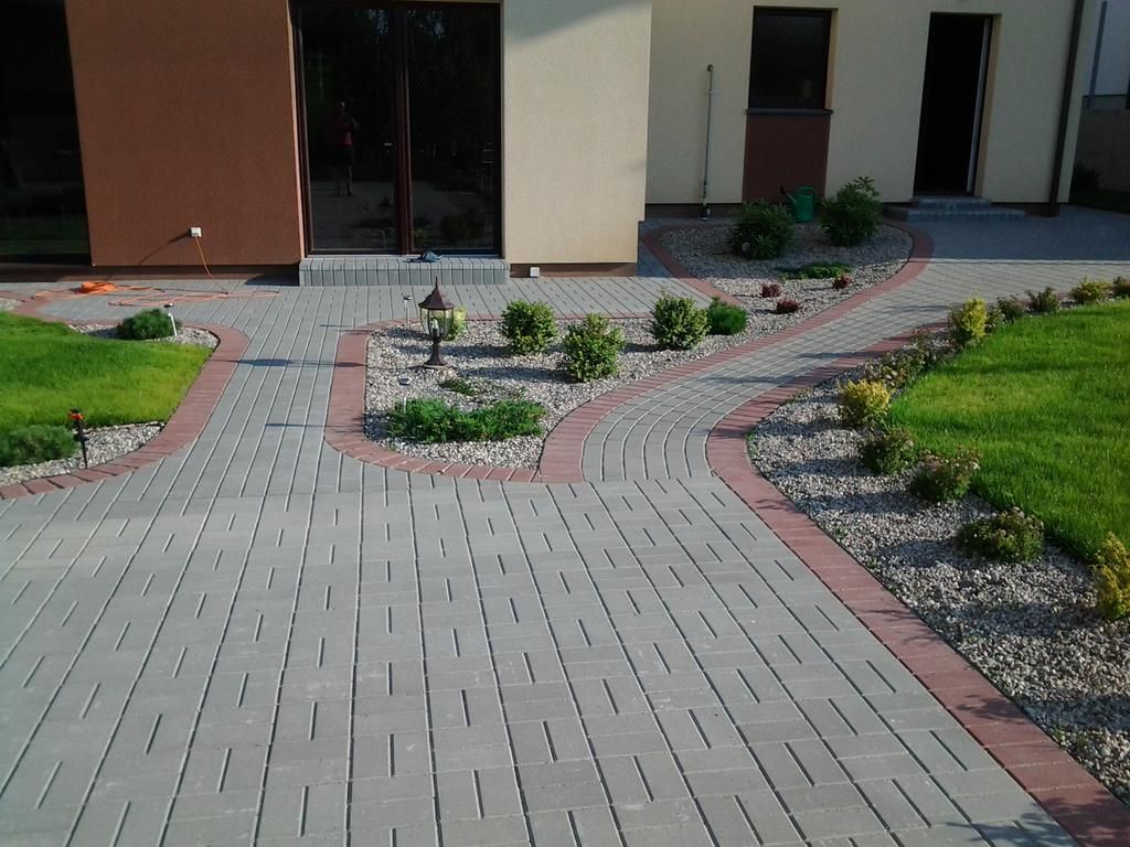 Trinkelių grindinys su raudonais kraštais prie namo