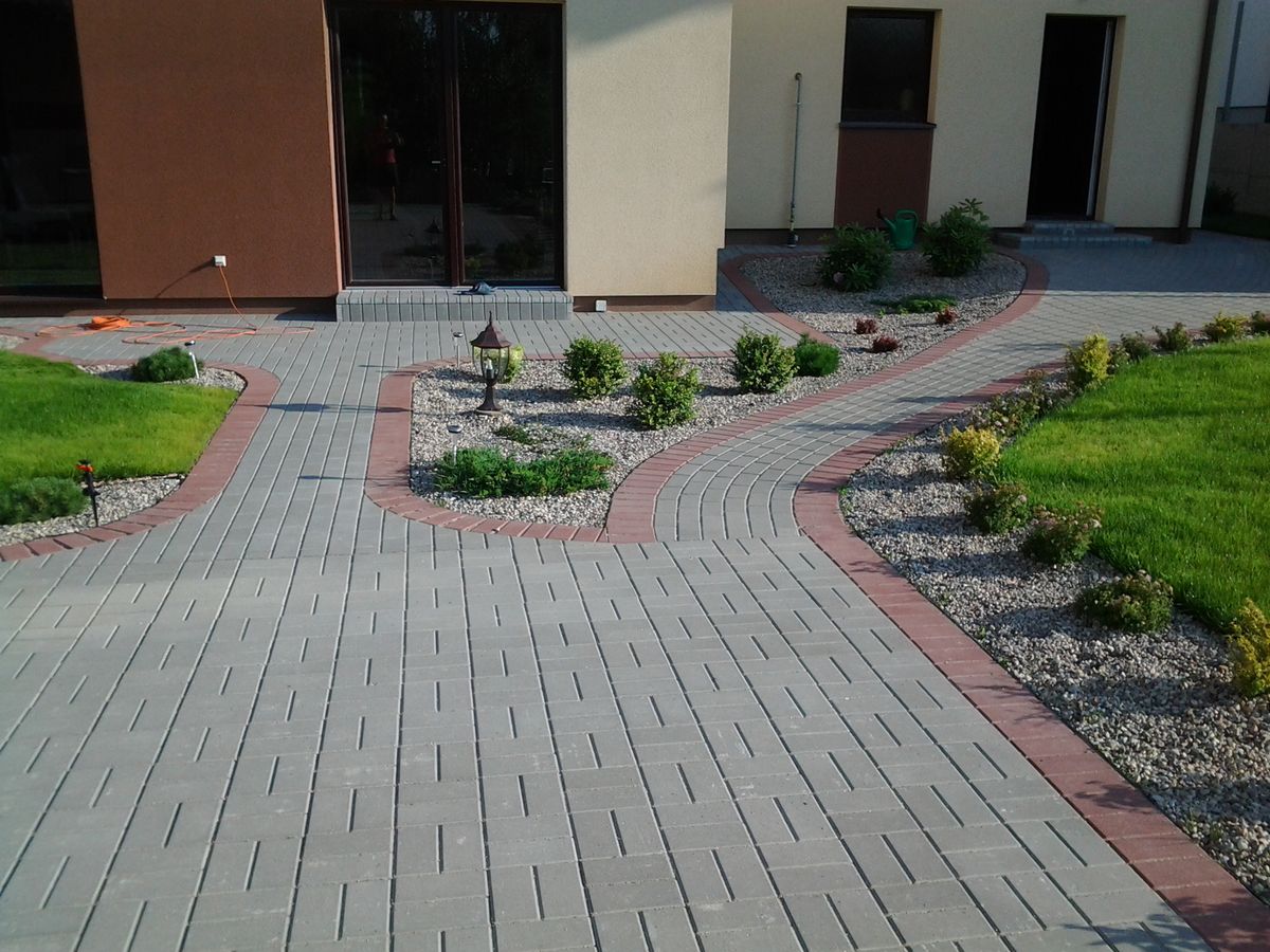 Lenktas trinkelių grindinys su apželdintu kiemu